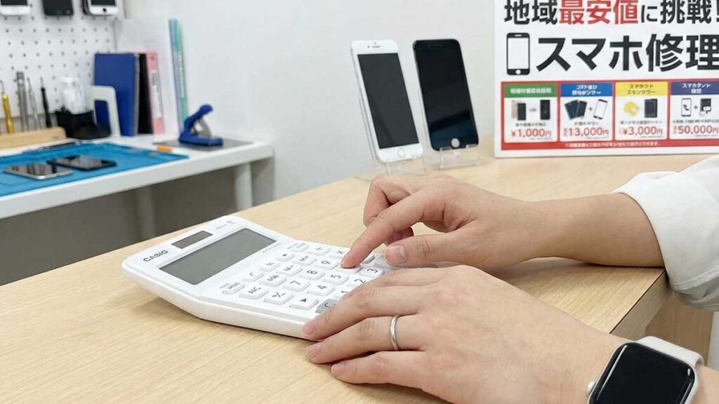 店員が電卓で修理料金を計算している